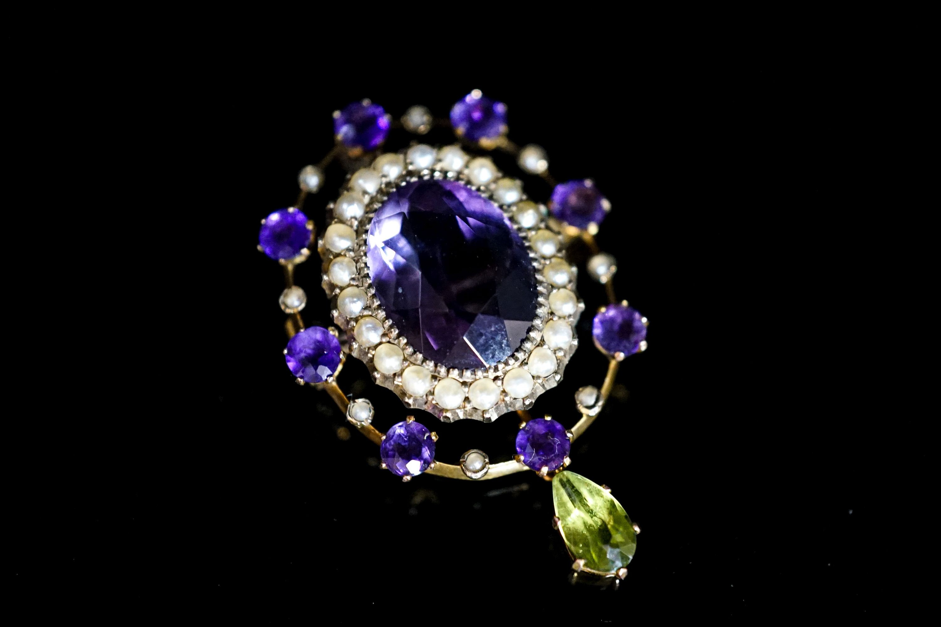 An early 20th century yellow metal, amethyst and peridot set drop oval brooch, in the suffragette colours, 35mm, gross weight 4. 6 grams.